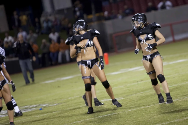 three girls in sports uniform walking across a field