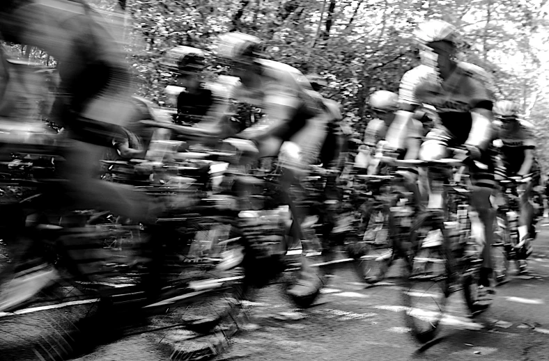 the b & w image shows a large group of men riding bikes