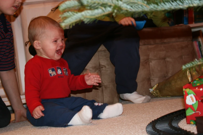 baby laughing while playing with toy cars by family