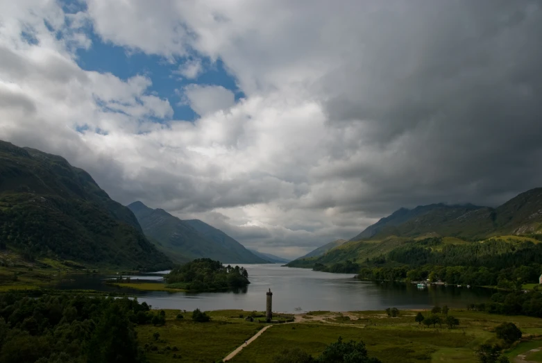 a lake surrounded by mountains under cloudy skies