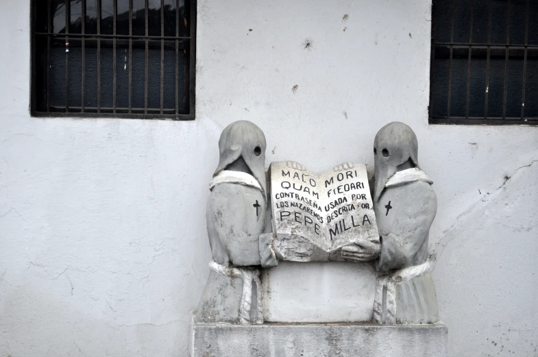 the birds are sitting on the cement with a sign