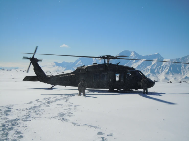 a black helicopter sitting on top of snow covered ground