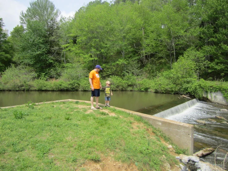 there is a man and boy on the bank of a stream