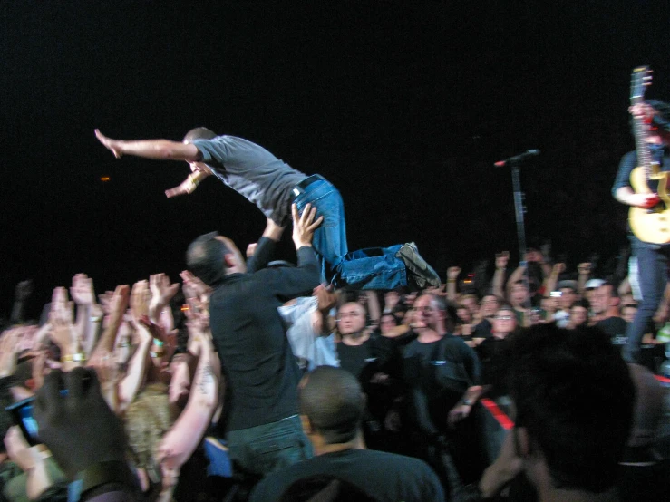 a man falling from his chair and doing a jump at a concert