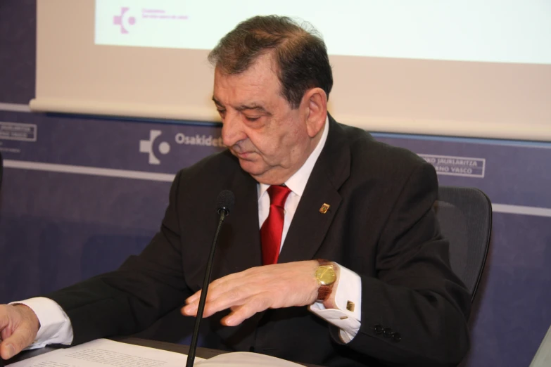 a person wearing a suit sitting at a table with papers