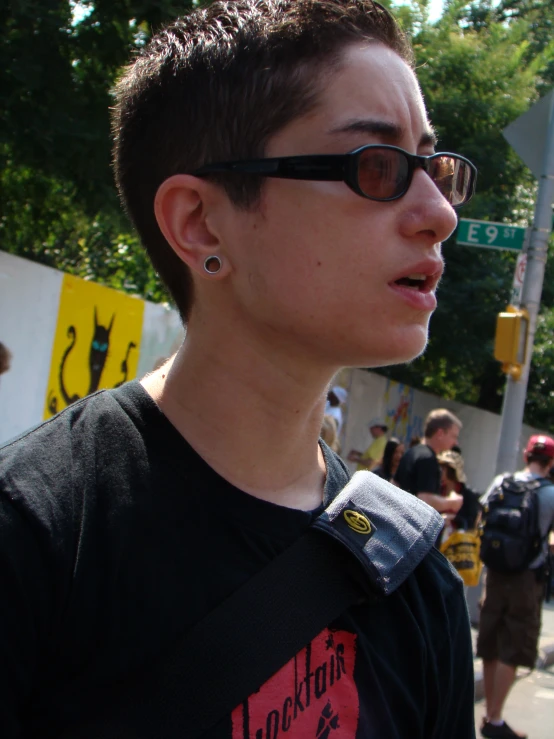 a young man wearing sunglasses while standing on the street