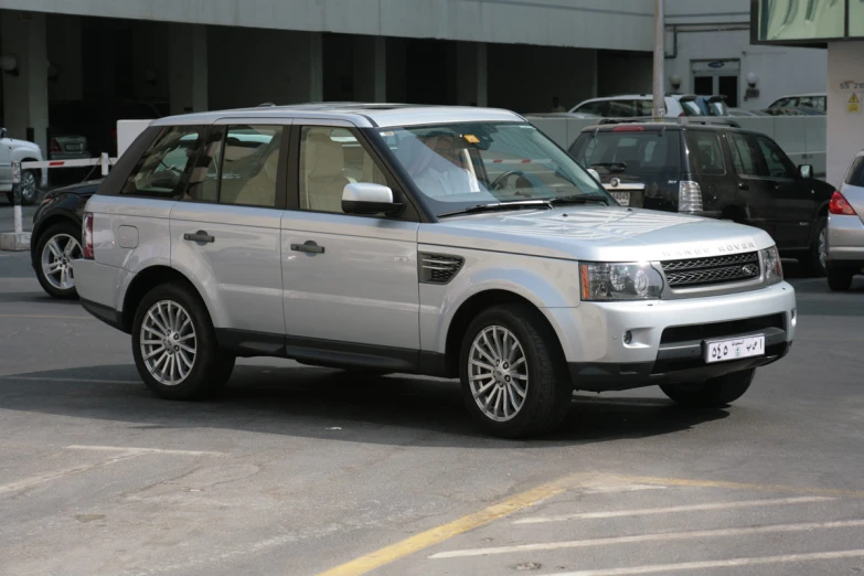 a grey range rover parked in parking lot with another vehicle nearby