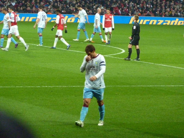 a man walks on the soccer field as others watch