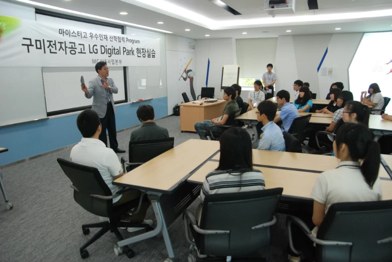 a group of people in a classroom with laptops