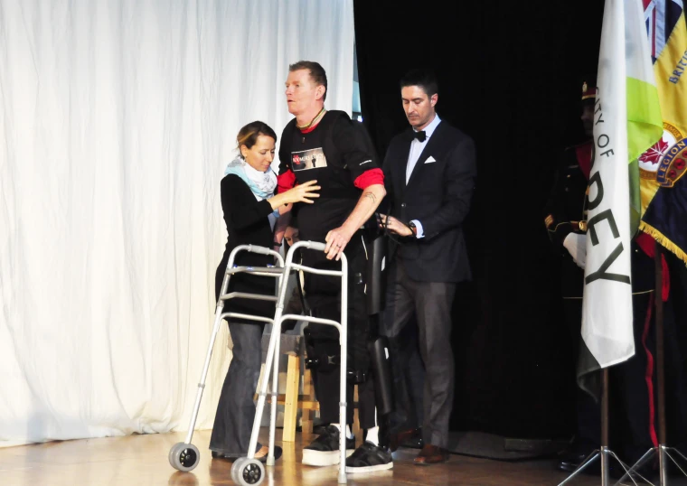 a man in a wheelchair stands between two other men