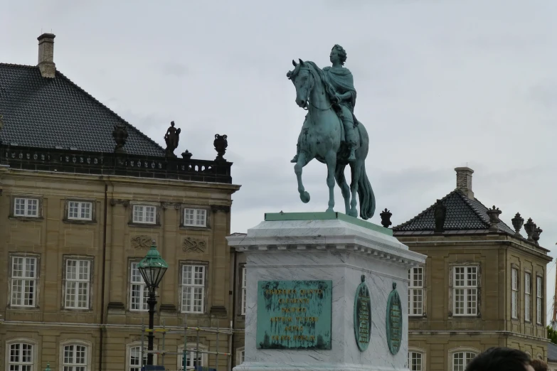 the statue of an old man riding a horse in front of several old buildings