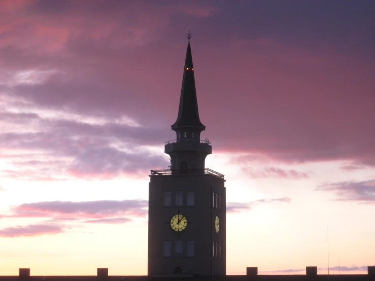 this church tower is at sunset under a pink sky