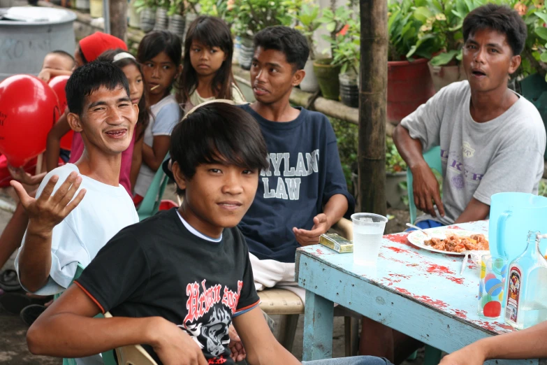 a group of boys sitting around a table with food and balloons