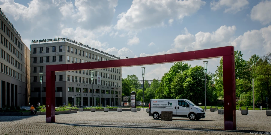 a white van driving under a tall arch