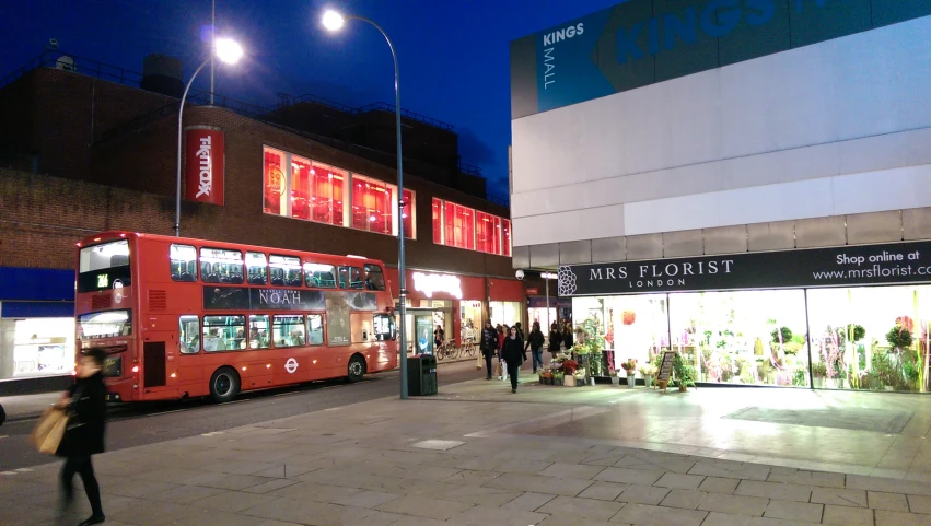 a red double decker bus sitting at the entrance to a store