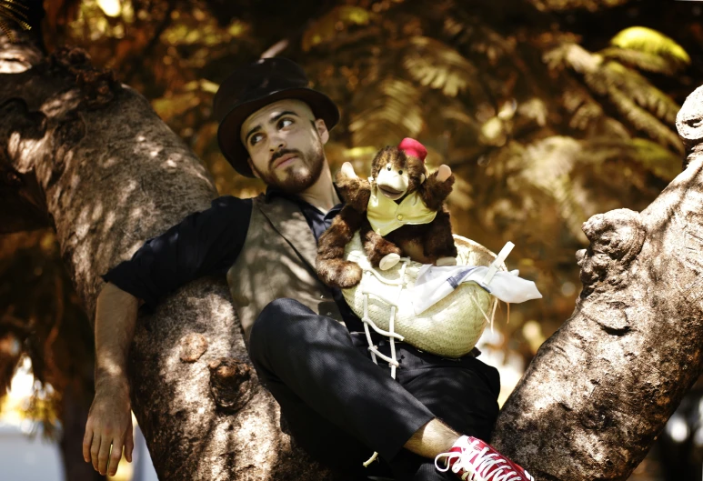 a man wearing a hat holding two small baby animals in his arms