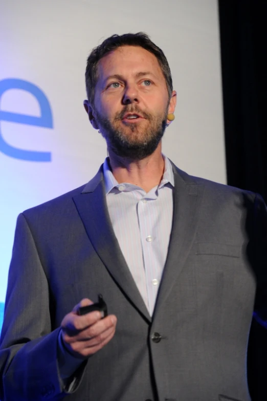 man in gray suit standing in front of a wall