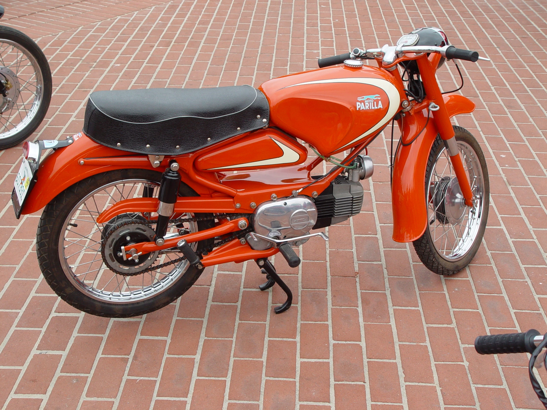 an orange motorcycle parked on top of a brick road