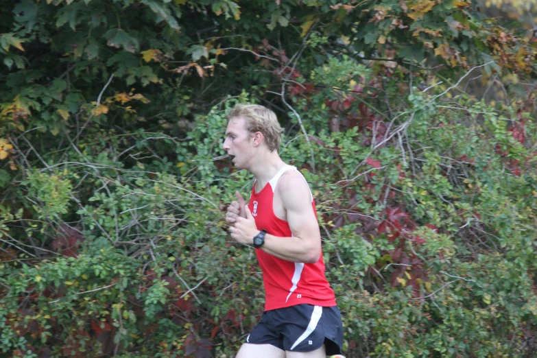 a man in running clothing with a red shirt and black shorts