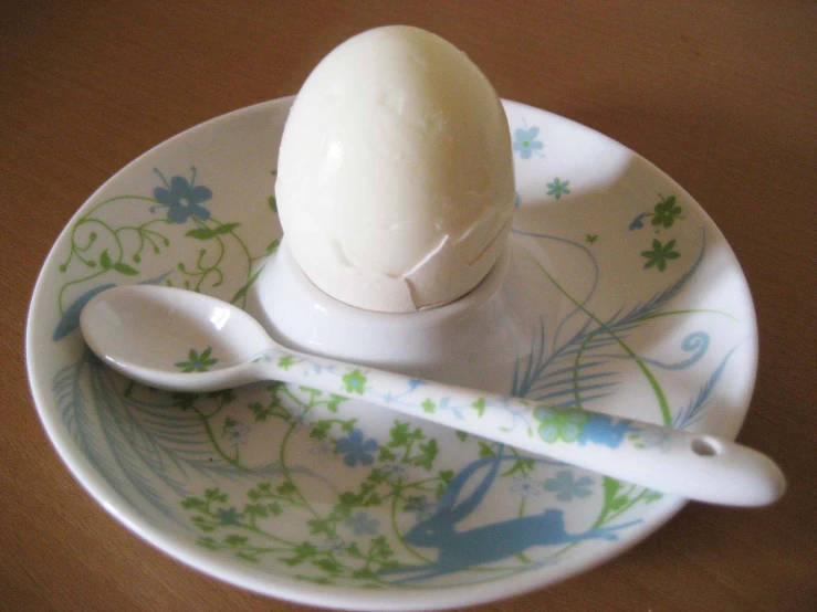 an egg on a plate with two spoons