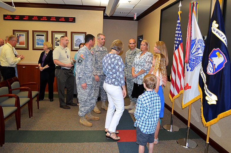 several military personnel and a  standing near flags