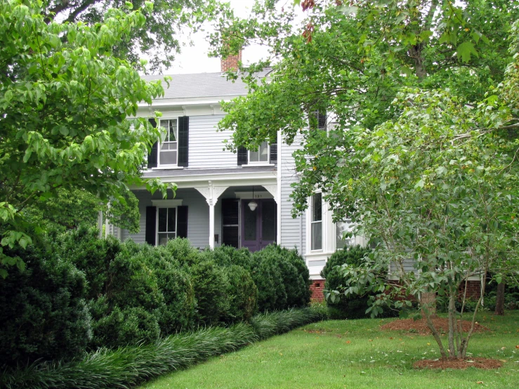 a white two story house with lush green grass on the lawn