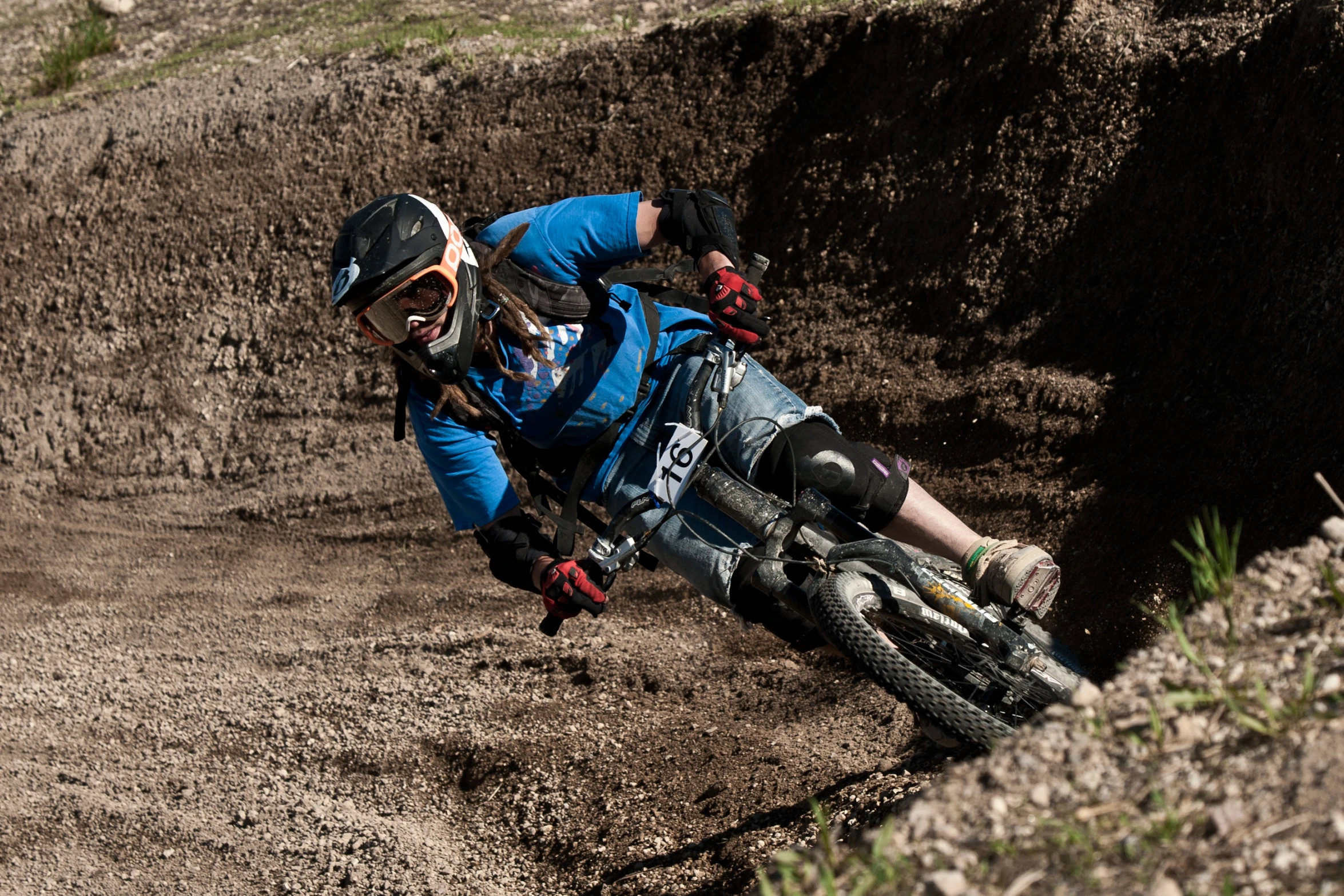 a dirt bike rider in blue shirt on a dirt track