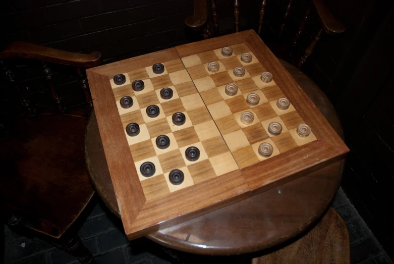 a chess board sits on a stool in front of a wall