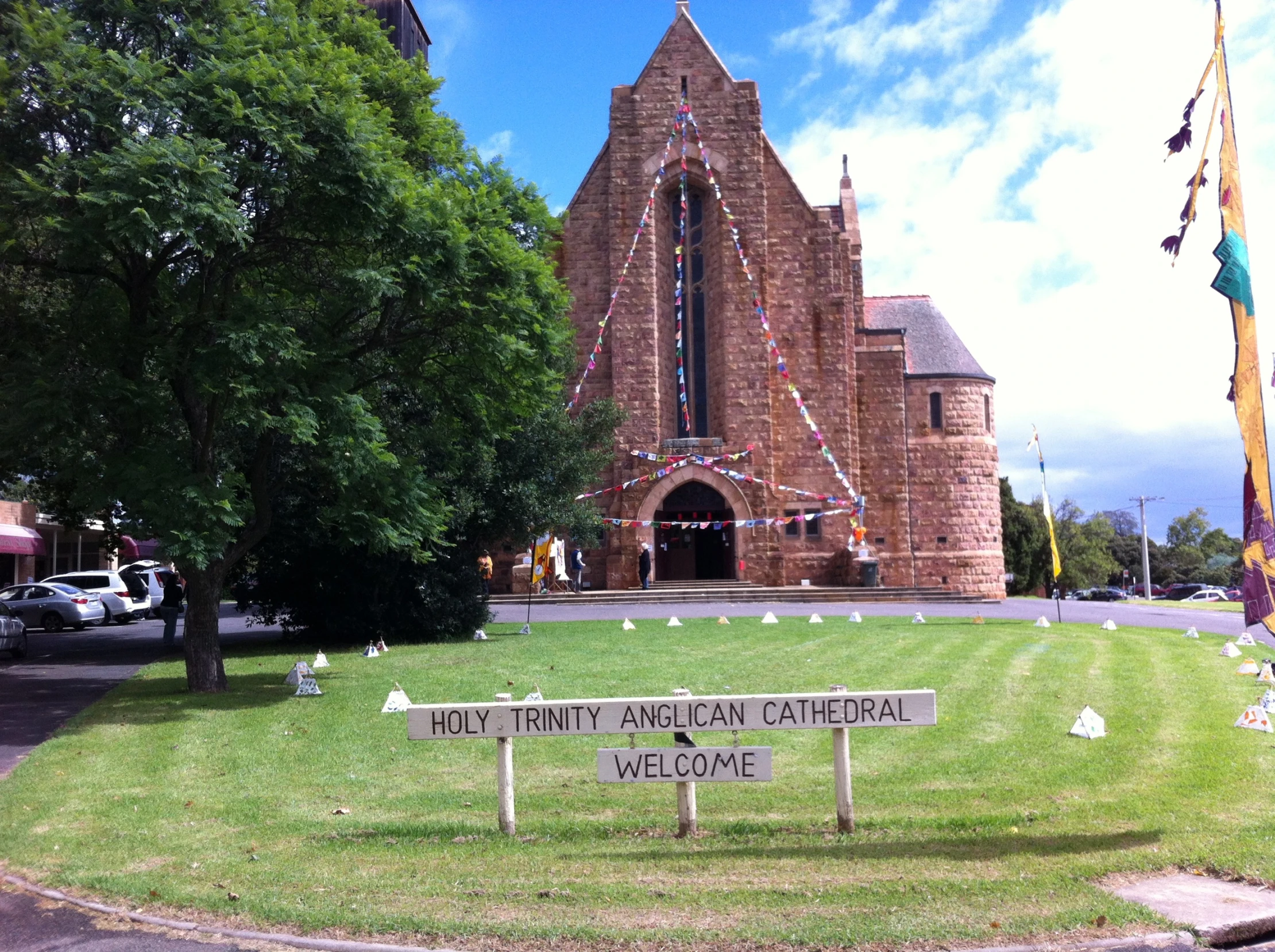 a church with a yard that has various small trees in front of it