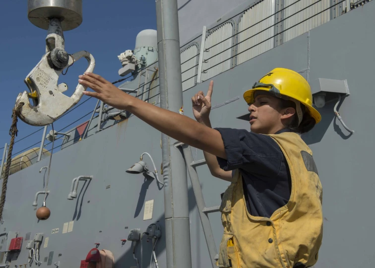 a man in yellow hard hat on a navy ship