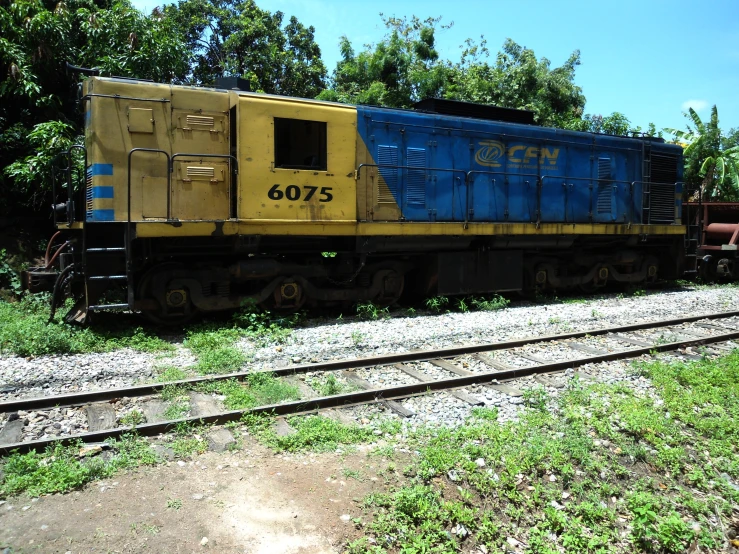 a yellow, blue and brown train car sitting on the tracks