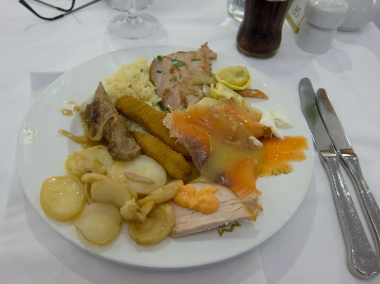a plate of food with silverware on a white table