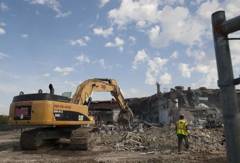 a bulldozer is on a construction site near a building that's being demolished