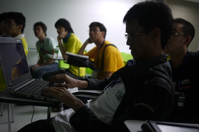 men working on laptop computers in a large room