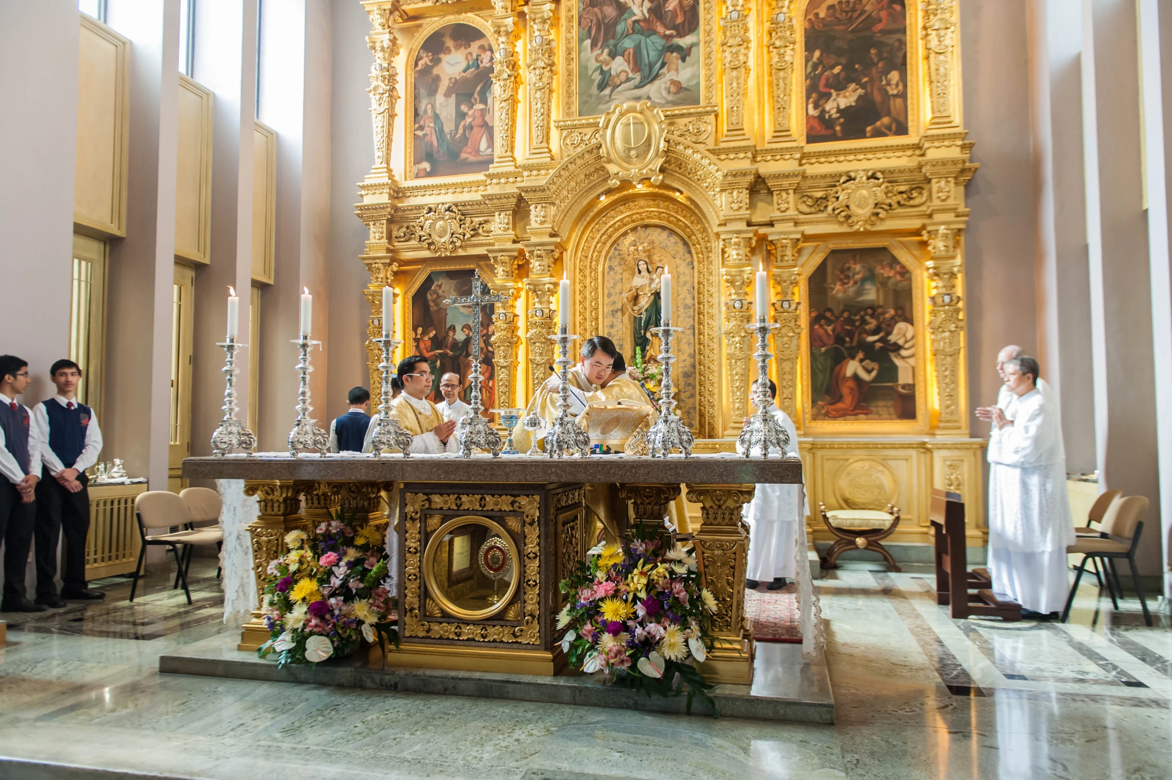 priest at the alter of ornate church altar with women and men