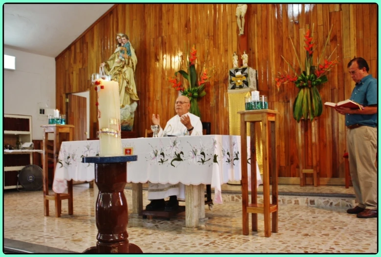 a man in white sitting at a table in front of a statue