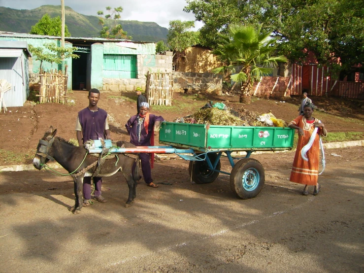 three people standing beside a horse and cart