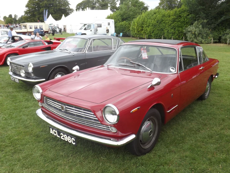 two classic sports cars parked in the grass at a car show