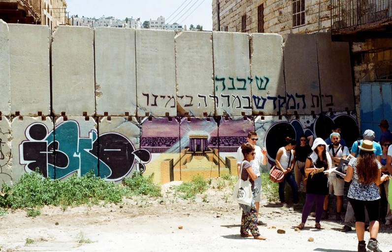 people are walking down the street in front of graffiti