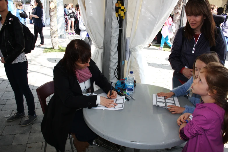 three little girls are gathered around a table together