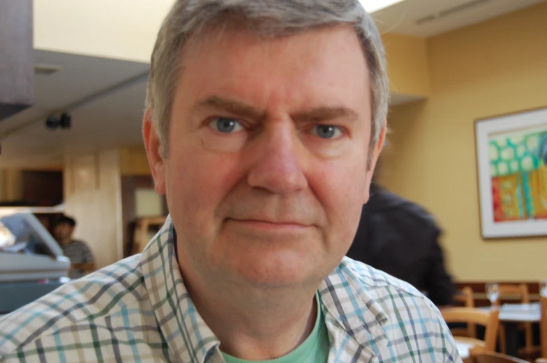 a man with gray hair sitting down and posing for the camera