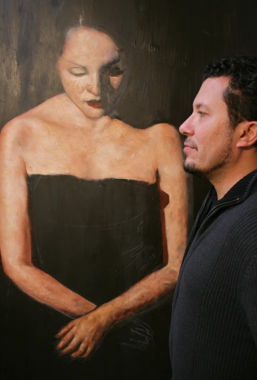 a man is standing in front of a painting of a woman