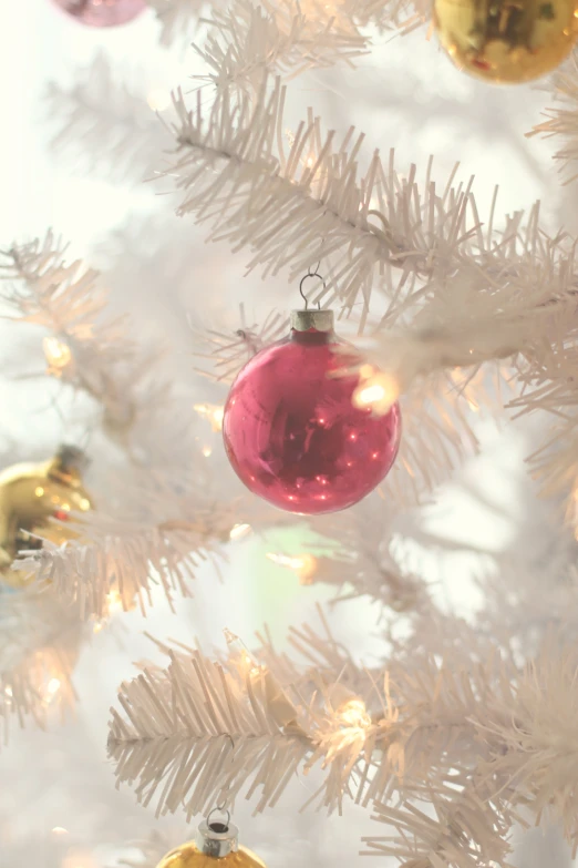 a white christmas tree with yellow and pink ornaments