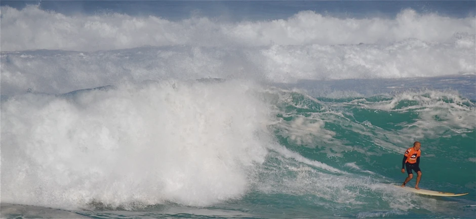 surfer in wet suit catching big wave with crashing white foam