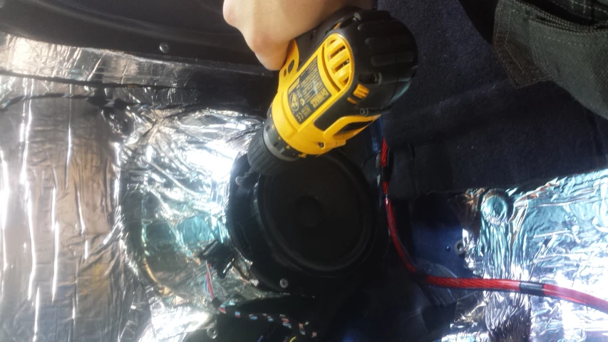 a person holding a power tool while inside a car