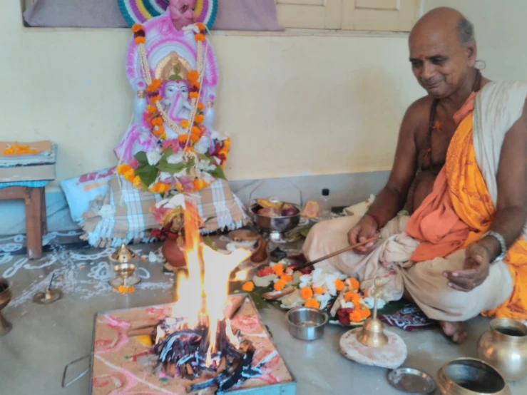 man sitting around with bowls and a lit candle on the floor