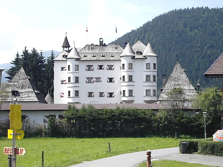 a white building with three large towers is next to a road