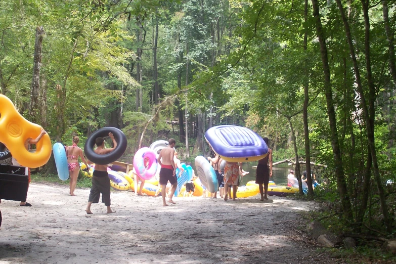 a group of people playing in the sand with several floating toys