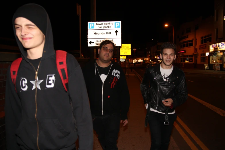 a couple of young people walking down a street at night