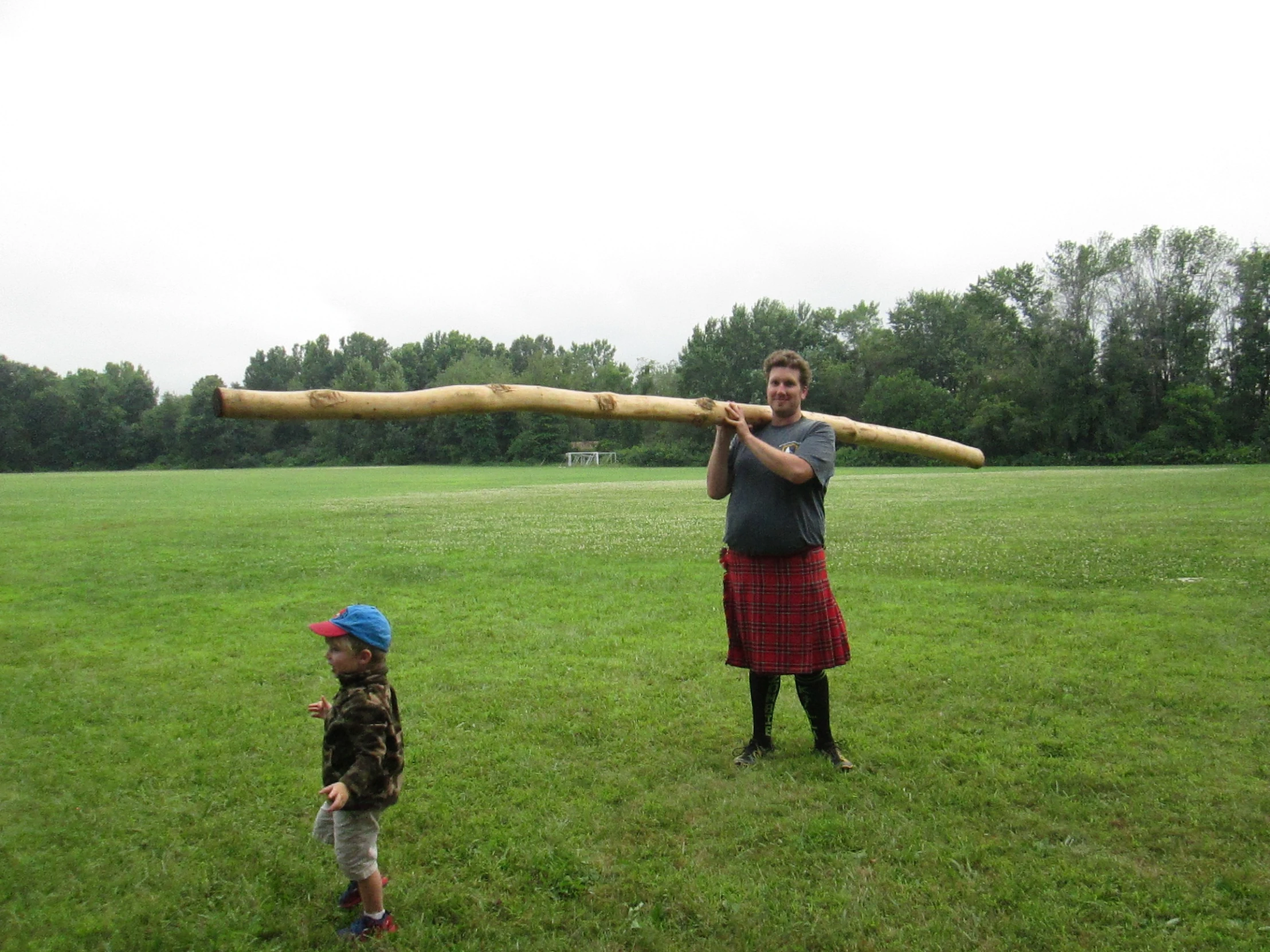 a man standing next to a small boy holding a baseball bat